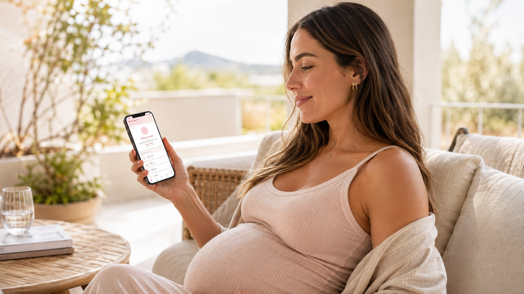 Embarazada usando la app Kalma en el móvil, relajada en su terraza.